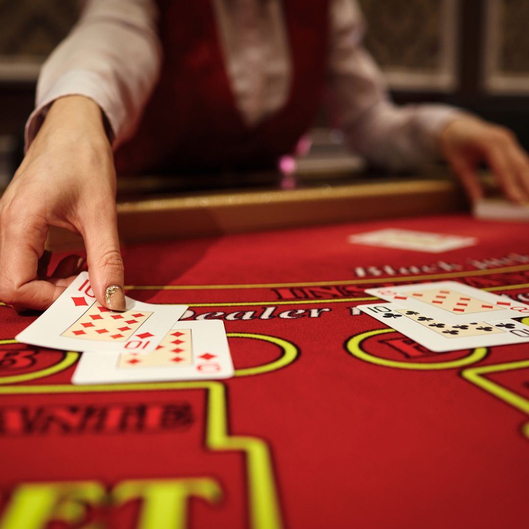 Croupier placing down a ten of diamonds on a red blackjack table in a casino